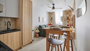 A modern kitchen with wooden cabinets, a black sink, and a dining area with a wooden table and chairs.