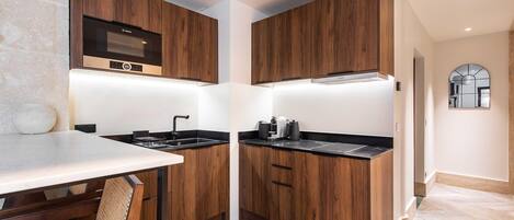 Una cocina compacta con armarios de madera, horno empotrado y encimera con lavabo.