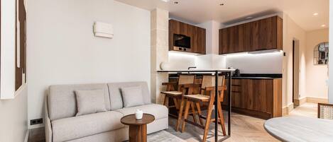Una sala de estar moderna con un sofá, una mesita redonda y un comedor con sillas de madera y una mesa.