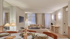 Une chambre d’hôtel moderne dotée d’un coin repas, d’un canapé et d’un grand miroir.