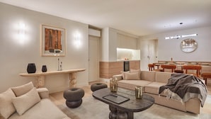 Un salon moderne avec un canapé, une table à manger et un coin cuisine à l’arrière-plan.
