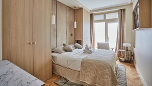 Ein Schlafzimmer mit Bett, Kleiderschrank, Nachttisch, Lampe und einem Fenster mit Vorhängen.