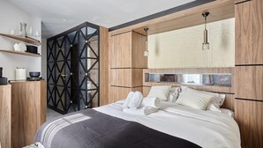 A modern bedroom with a large bed, wooden paneling, a geometric black partition, and a hanging light fixture. - Magnificent New Studio Louvre Palais Royal (Paris)