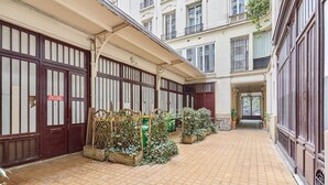Une cour avec un sol carrelé, des clôtures en bois et des plantes en pot.