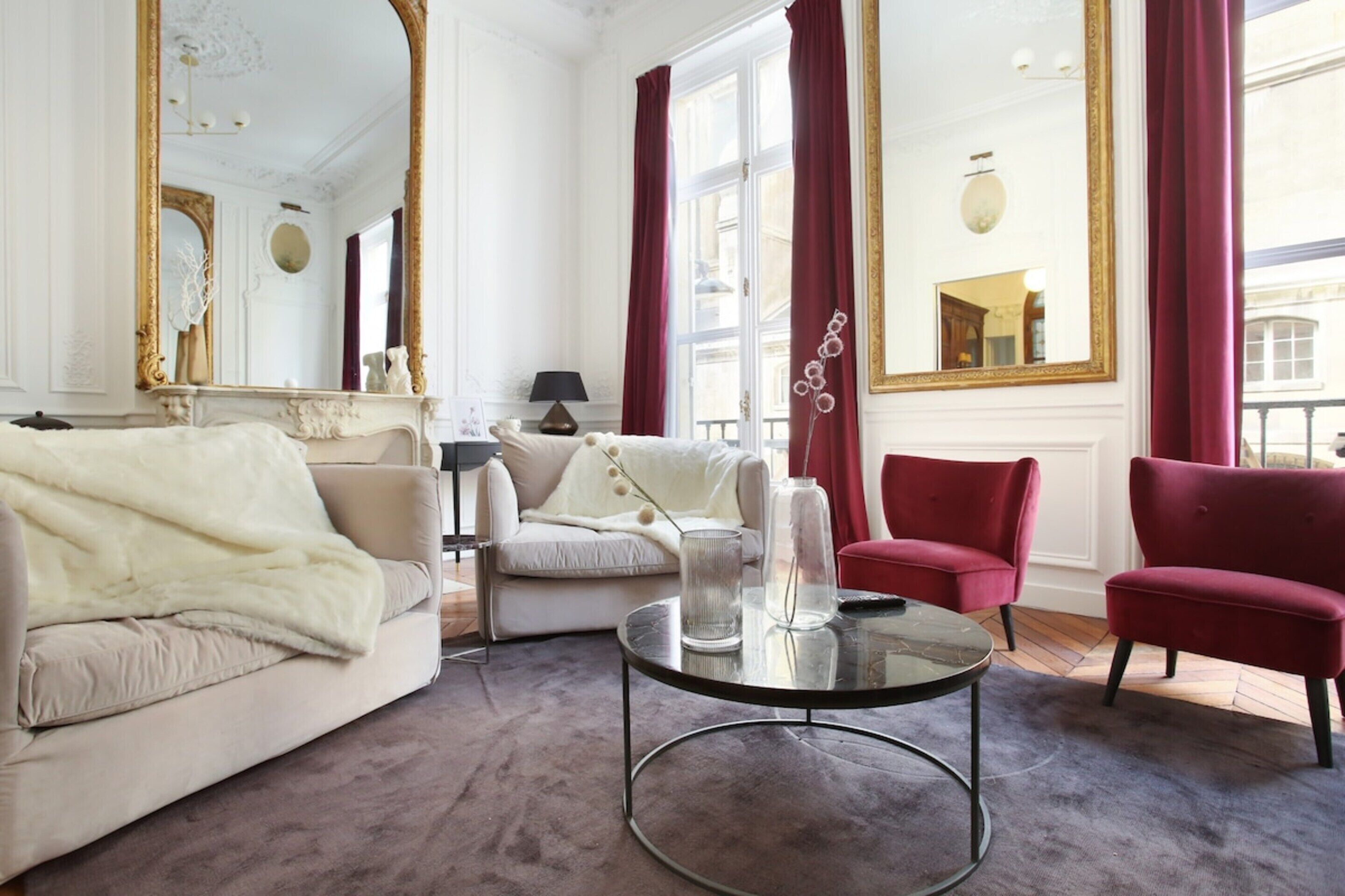 Ein Zimmer mit einer Couch, Sesseln, einem Glastisch und einem Spiegel.