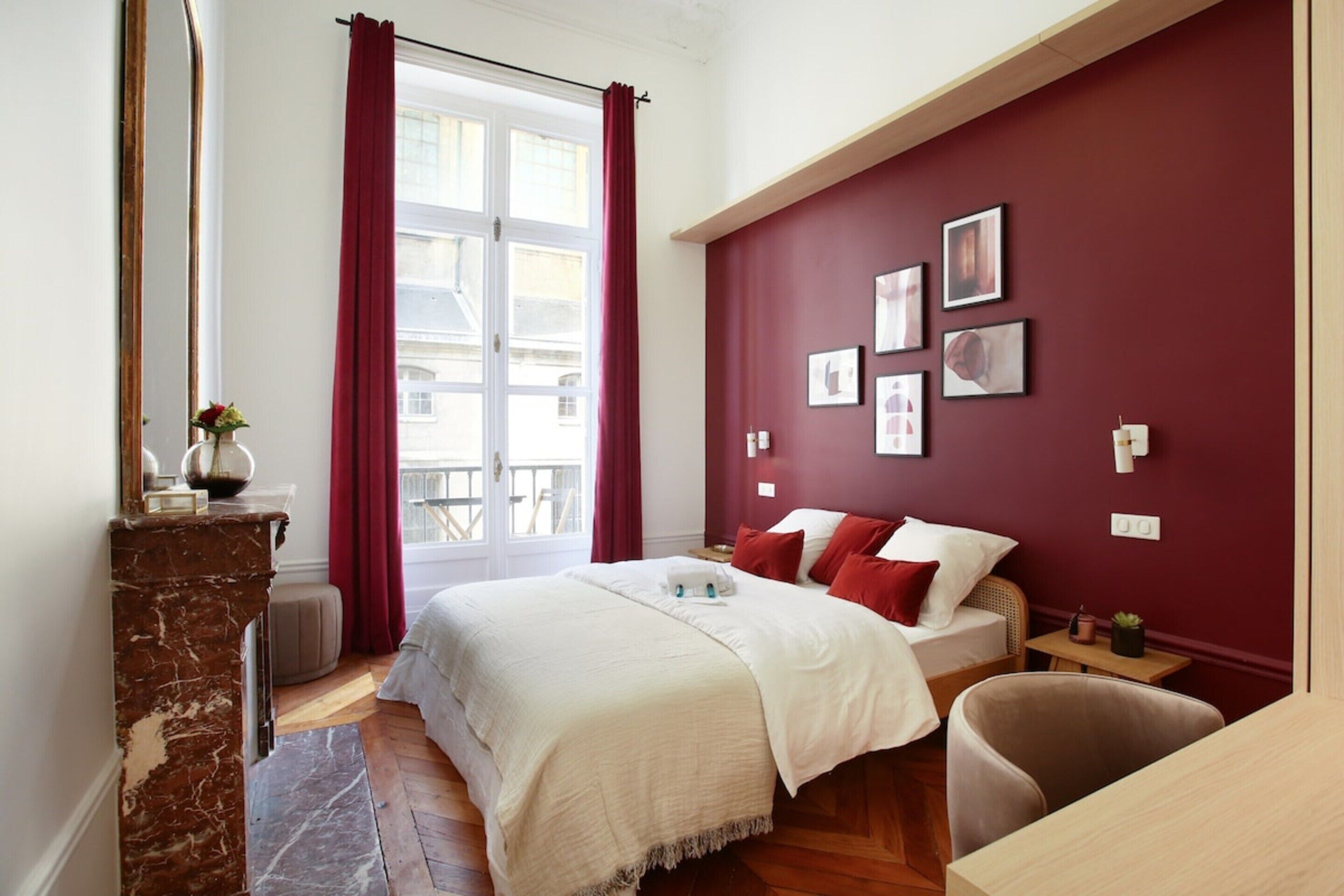 Una camera da letto con un letto, una scrivania in legno, uno specchio e una finestra con tende.