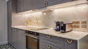 A modern kitchen with grey cabinets, a marble countertop, a built-in oven, and a coffee machine. - Sublim & New Aparment Saint Germain des Pres (Paris)