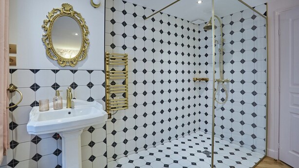 A bathroom with a white sink, gold fixtures, a mirror, and a shower with a geometric tile pattern. - Sublim & New Aparment Saint Germain des Pres (Paris)