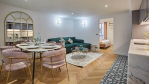 A modern living room with a green sofa, a dining table with pink chairs, and a large mirror. - Sublim & New Aparment Saint Germain des Pres (Paris)