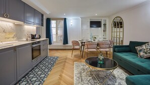 A modern kitchen with grey cabinets, a marble countertop, and a dining area with a table and chairs. - Sublim & New Aparment Saint Germain des Pres (Paris)