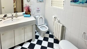 Een badkamer met een zwart-wit geruite vloer, een witte wastafel met spiegel, een toilet en een radiator.