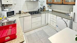 Een moderne keuken met witte kasten, een roestvrijstalen afzuigkap, een magnetron, een gasfornuis en een geïntegreerde vaatwasser.