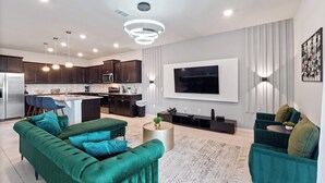 A modern living room with a green sofa, a coffee table, and a TV mounted on the wall.