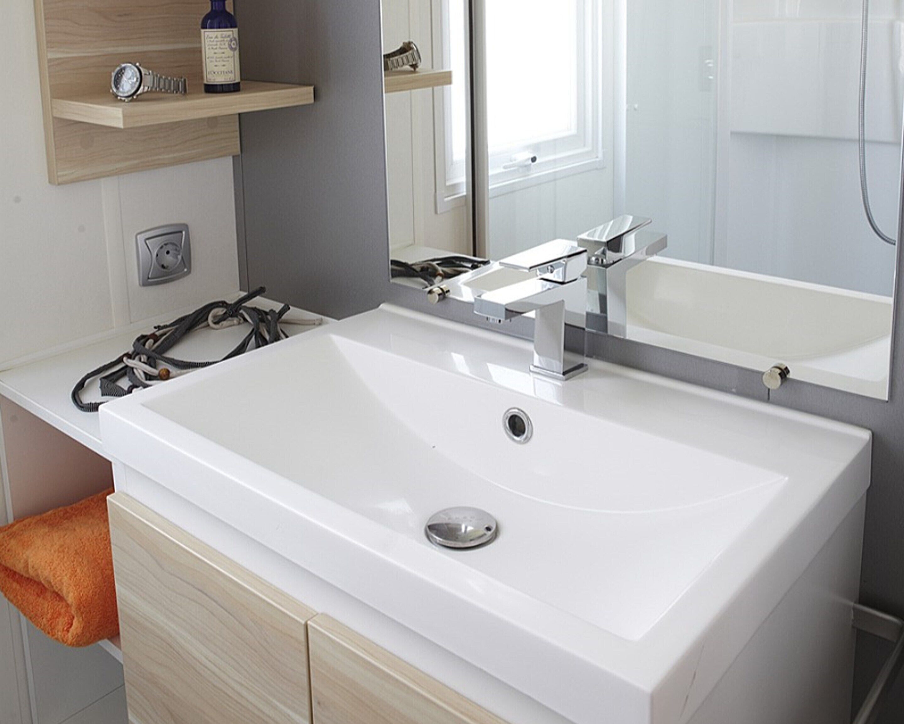 A modern bathroom with a large white sink, a mirror, and a towel rack.