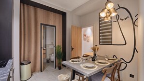 Un comedor moderno con un separador de madera, una mesa de comedor dispuesta con platos y vasos, y una lámpara fijada a la pared.