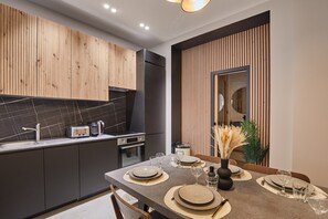 Enjoy a meal at the dining table, surrounded by sleek cabinetry and a stainless steel refrigerator.