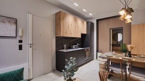 Una cocina moderna con encimeras oscuras, armarios de madera y una zona de comedor con mesa y sillas de madera.