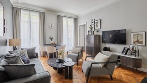 A modern living room with a sofa, armchairs, a coffee table, and a TV. - Superb New 1 Bedroom Flat Notre Dame de Paris (Paris)