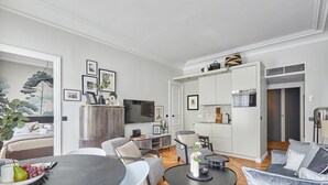 A modern living room with a dining table, sofas, and a kitchen area with a TV and appliances. - Superb New 1 Bedroom Flat Notre Dame de Paris (Paris)