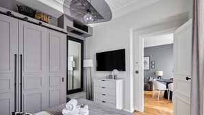 A modern bedroom with a large bed, a wardrobe, a desk, and a television. - Superb New 1 Bedroom Flat Notre Dame de Paris (Paris)