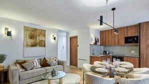 Una sala moderna con una mesa de centro de vidrio, un sofá con cojines y un comedor con una mesa redonda dispuesta para seis.