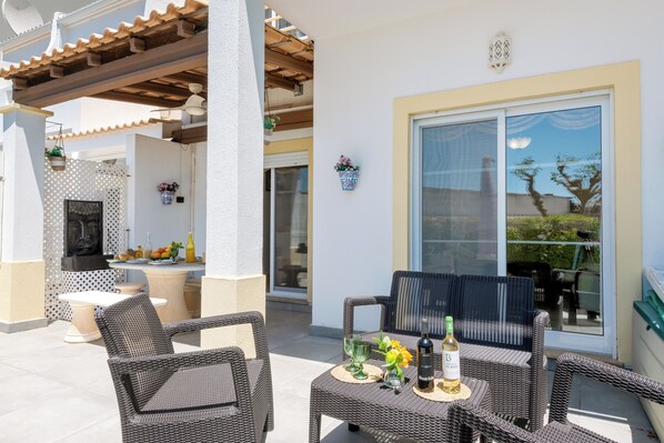 An outdoor patio with wicker furniture, a table with drinks, and potted plants. - Villa Magdalena - near Albufeira (Guia)