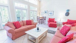A bright living room with striped red sofas, a wooden coffee table, and a dining area with a table and chairs. - Back on the Rental Market! Dog-Friendly, 4BR/4BA w/ Pool! (St. George Island)