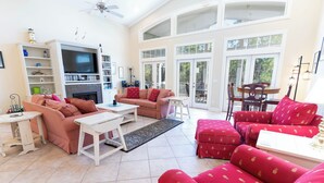 A spacious living room with a fireplace, a television, and a dining area with a table and chairs. - Back on the Rental Market! Dog-Friendly, 4BR/4BA w/ Pool! (St. George Island)