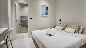 A bedroom with a bed, a chair, a radiator, a poster, and a door.