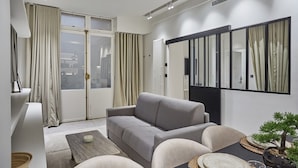 A modern living room with a grey sofa, a coffee table, and a dining area with a black table.