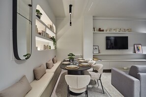 Un espace repas moderne avec une table ronde prévue pour quatre personnes, entourée de canapés et de fauteuils.