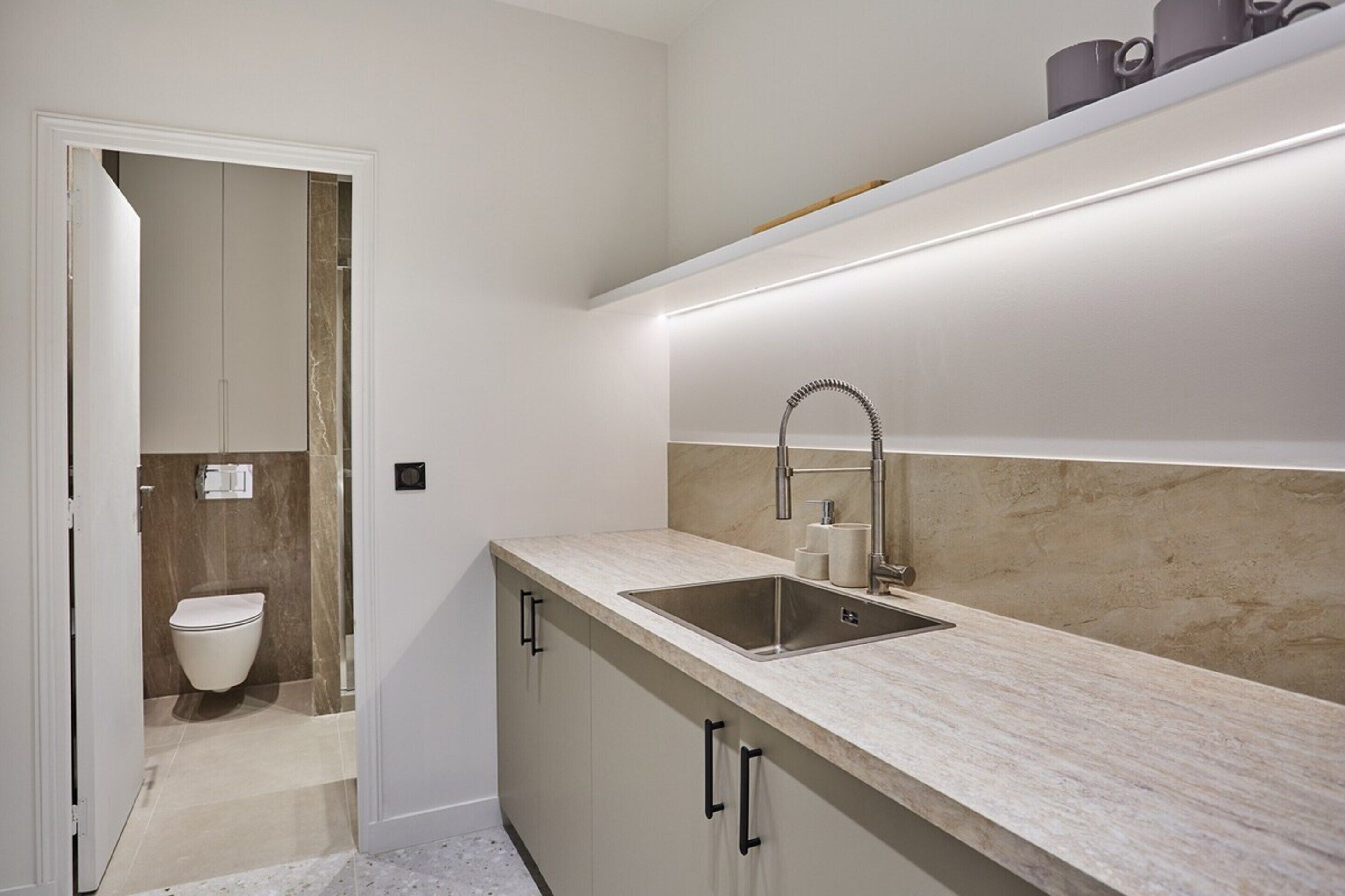 A compact kitchen with a sink, countertop, and a door leading to a bathroom.