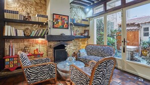 A cozy living room with a fireplace, bookshelves, and zebra-print furniture. - Superbe Apartment Le Marais/place des Vosges (Paris)
