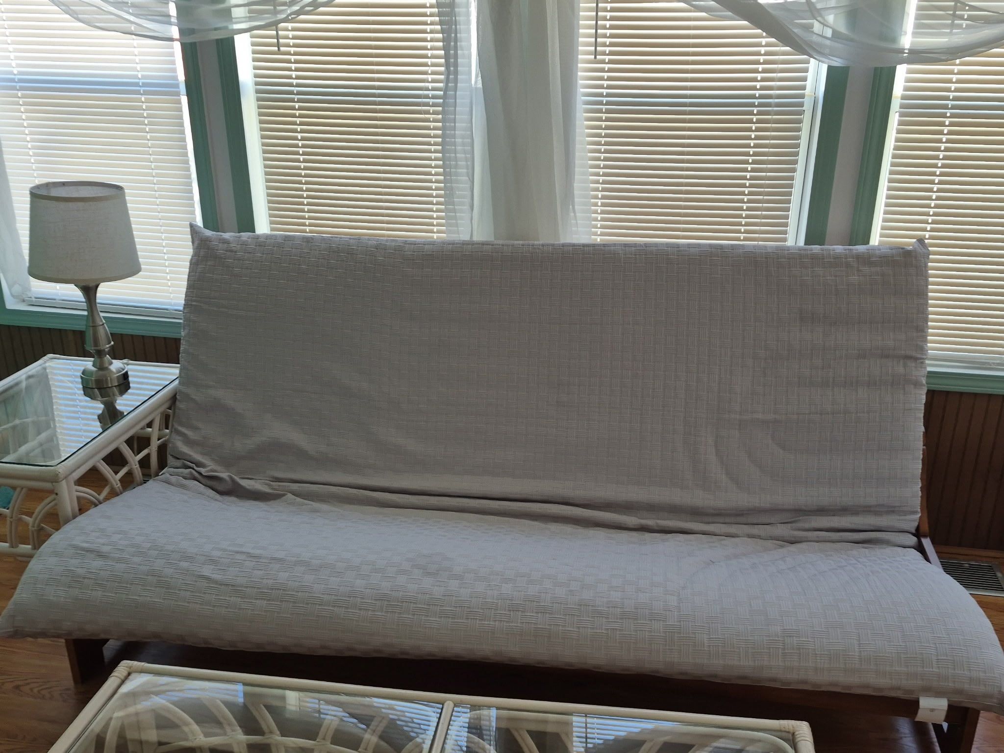 Un canapé au revêtement texturé, une table basse en verre et une lampe sur une table d’appoint.