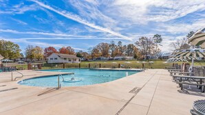 A swimming pool with a fountain, surrounded by picnic tables and a fenced area.