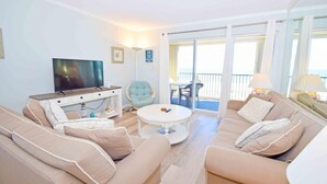 Ein Wohnzimmer mit Fernseher, Sofa, Couchtisch und einem Balkon mit Blick.