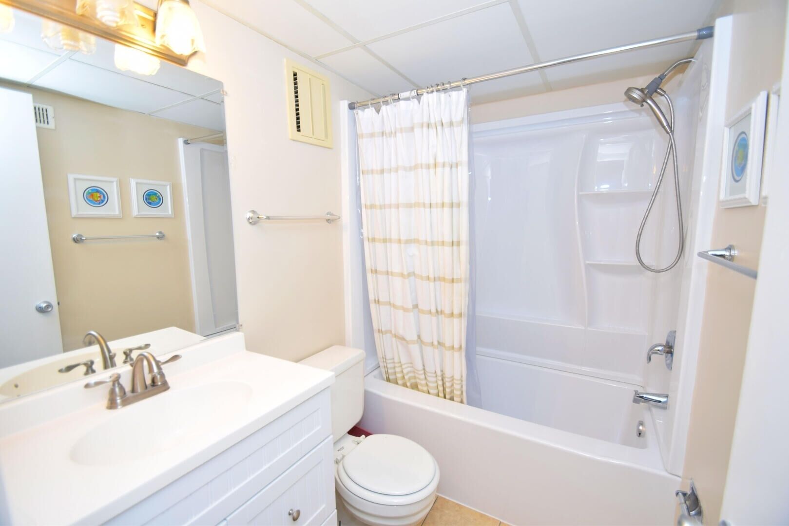 Un baño con lavamanos blanco, espejo, inodoro y zona de ducha con cortina.