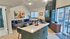 Une cuisine moderne dotée d’un îlot central, d’un coin repas avec un canapé et d’une grande fenêtre donnant sur l’extérieur.