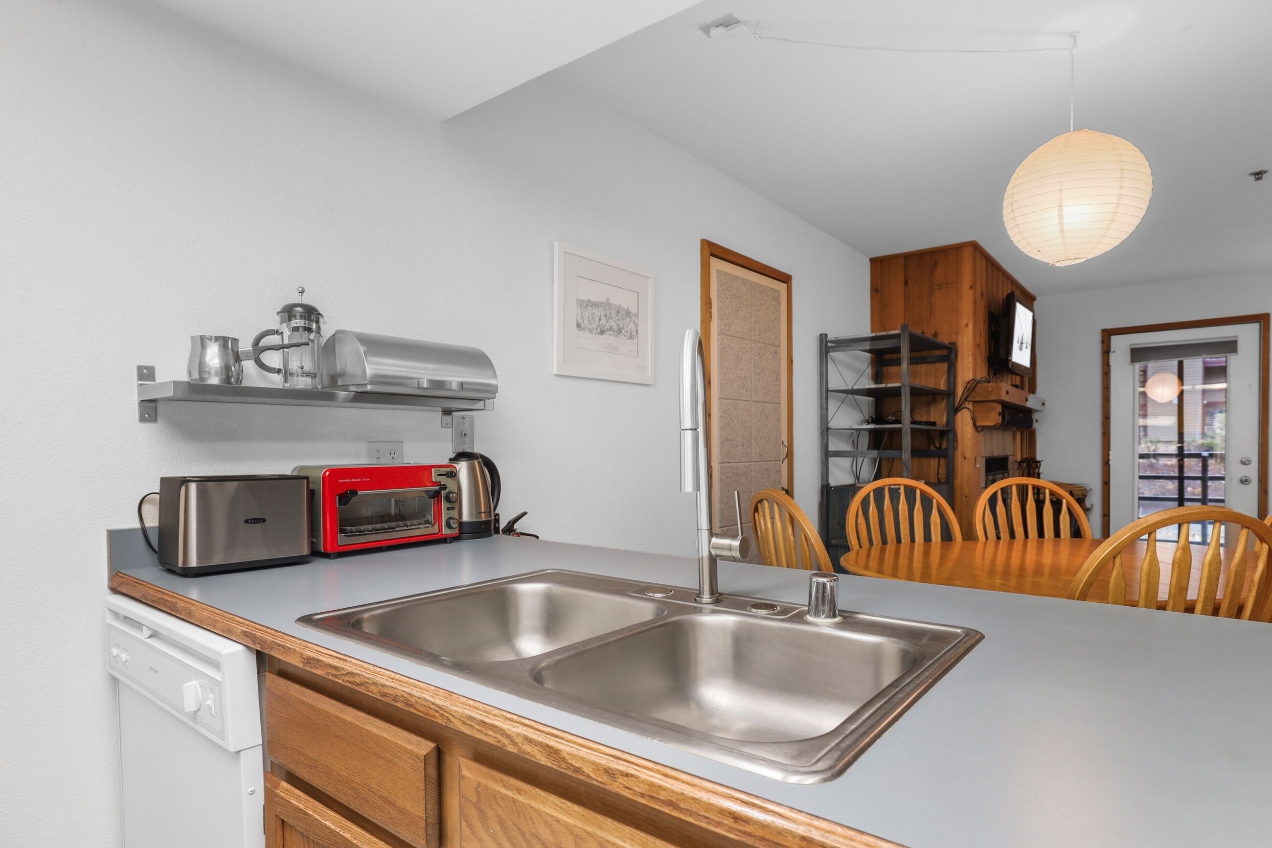 A modern kitchen with stainless steel appliances, a wooden dining table, and chairs.