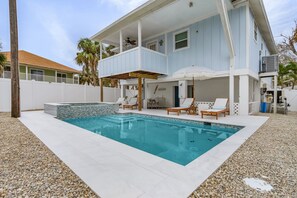 Une maison à deux étages dotée d’une piscine, d’un espace extérieur aménagé pour se détendre et d’un patio couvert.