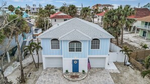 Ein hellblaues Haus mit rotem Dach, einer Garage und einer Veranda mit einer kleinen amerikanischen Flagge.