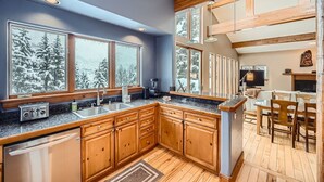 Una cucina moderna con armadietti in legno, piani in granito e una grande finestra con vista su un paesaggio innevato.