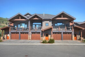 A large, modern two-story house with a covered front porch, multiple garage doors, and a balcony on the upper floor. - Luxury Home - Sleeps 10 - Fireplace & Mountain View 3 Bedroom Condo (Keystone)