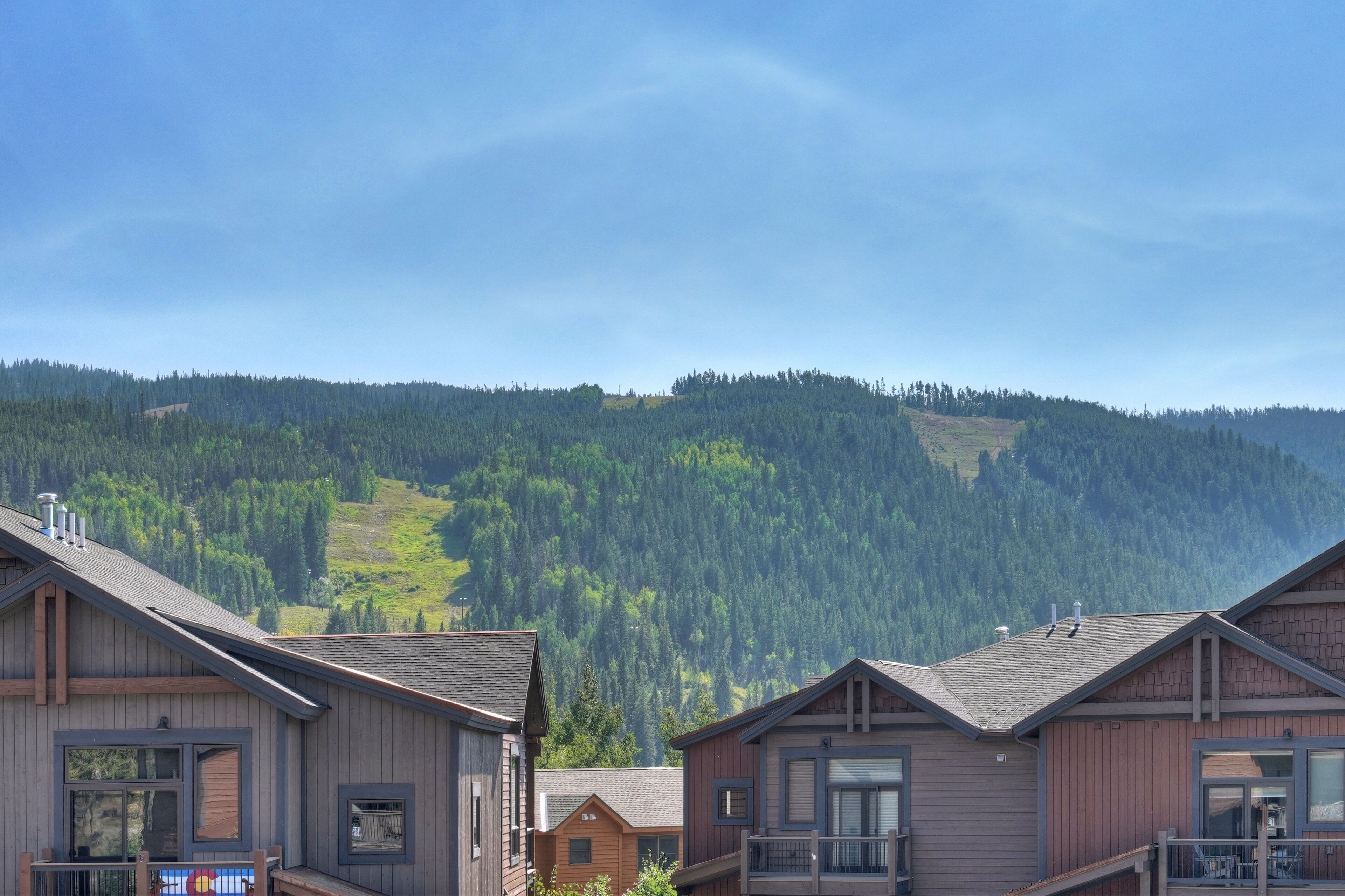 Une rangée de cabanes en bois, avec une montagne boisée en arrière-plan.