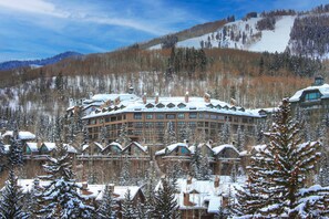 Un grand chalet comprenant plusieurs bâtiments, entouré d’arbres couverts de neige et adossé à une montagne.