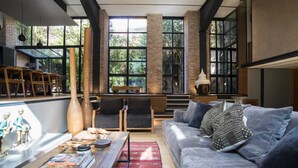 A spacious living area with a large gray sofa, wooden coffee table, and a view of lush greenery through tall windows. - SPAZIOPANIERI
Up to 10 guests in a mix of luxury and orient with spa and terrace (Roma)