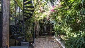 A spiral staircase leading to a covered outdoor area with a brick floor and lush greenery. - SPAZIOPANIERI
Up to 10 guests in a mix of luxury and orient with spa and terrace (Roma)