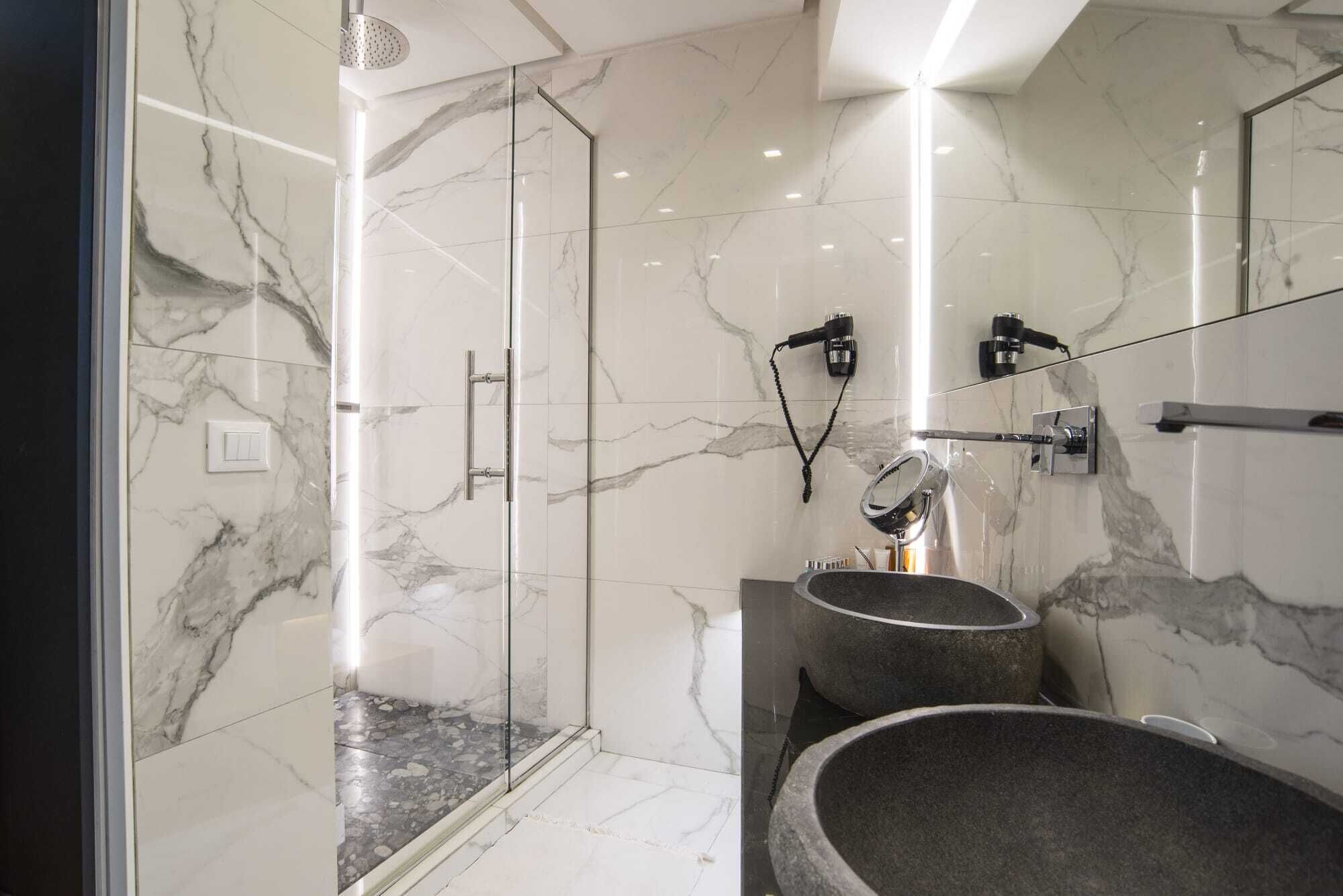 Un baño moderno con ducha de vidrio, paredes de mármol y un lavabo grande.