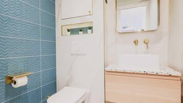 Ein Badezimmer mit Toilette, einem Waschbecken mit Marmorplatte, einem Spiegel und einer blau gemusterten Wand.