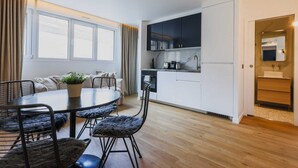 Un espacio habitable compacto con comedor, kitchenette y baño pequeño.